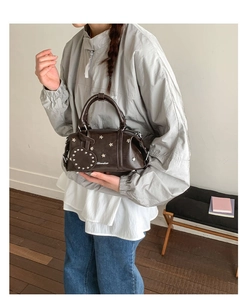 Détail du sac Boston marron foncé avec rivets étoiles argentés et breloque cœur