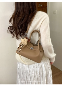 Détail du sac seau en cuir marron avec fermoir argenté, ours en peluche et perles