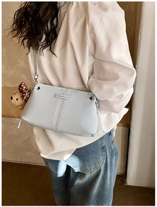 Detail of light blue faux leather crossbody bag with teddy bear charm and fashion label