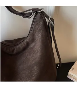 Detailed close-up of dark brown leather tote bag with silver metal ring and adjustable strap