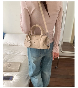 Sac Boston beige avec rivets en forme d'étoile et breloque cœur dans un décor de style vie