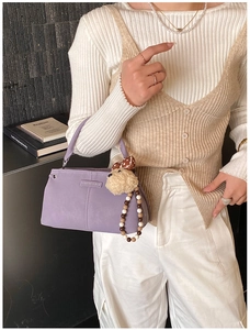 Chic lilac shoulder bag with plush charm and beaded strap worn by model in casual outfit