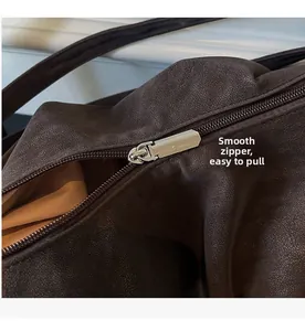 Close-up of smooth silver metal zipper and brown textured leather on large tote bag