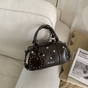 Détail du sac Boston vintage marron foncé avec clous en étoile sur un canapé beige