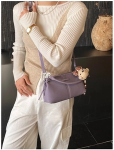 Detail of purple leather crossbody bag with a cute brown plush bear charm accessory