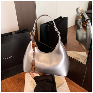 Detalle de bolso hobo plateado con colgante de cuentas de madera y acabado metálico brillante