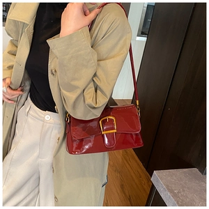 Detail einer dunkelroten Lackleder-Schultertasche mit einer großen goldenen Metallschnalle
