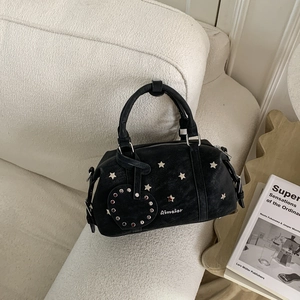 Détail du sac Boston noir en similicuir avec clous en étoile argentés et pendentif en cœur