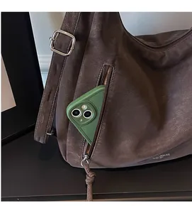 Detail view of the side zipper pocket on a brown faux leather tote bag with a smartphone