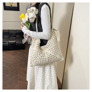 Detail showing hand-woven hollow texture and fringed tassel on a beige straw tote bag