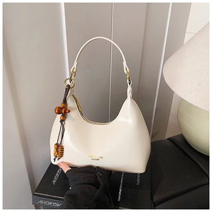 Detalle de un bolso de hombro blanco crema con textura suave y cuentas de madera decorativas