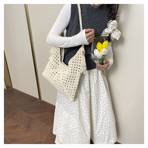 Beige hand-woven crochet shoulder bag with tassel detail styled on model's shoulder