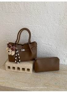 Détail d'un grand sac cabas marron foncé avec trousse assortie et chaîne perlée