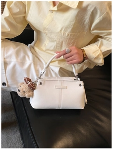 Detail of white PU leather crossbody bag with fashion plaque and brown plush bear charm