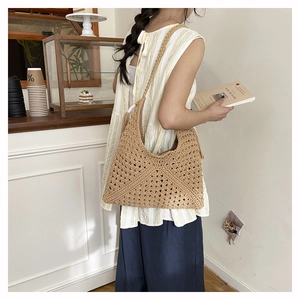 Detail of hand-woven straw shoulder bag with hollow floral patterns in a cafe setting