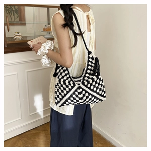 Detail of hand-crocheted black and white checkered tote bag with elegant side tassels