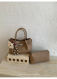 Détail macro du sac cabas en cuir grainé chameau avec fermoir en métal et petit ours