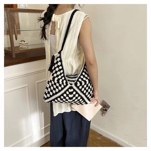 Side view of woman wearing black and white woven crochet tote bag with fringe