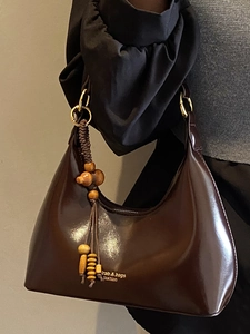 Bolso bajo el brazo marrón oscuro brillante con colgante de cuentas de madera y oro