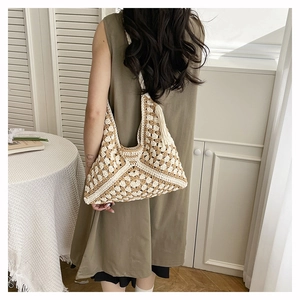 Close-up of handmade crochet shoulder bag with heart pattern and fringe detail