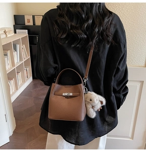Brown lychee leather bucket bag with silver twist lock and white bunny charm detail