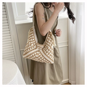 Detail of hand-woven straw tote bag with bohemian geometric pattern and stylish tassels