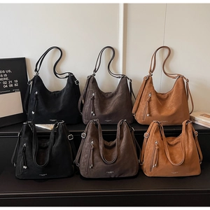 Detail view of large tote bags in black, dark brown and caramel suede texture finishes