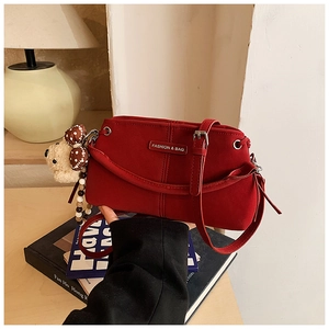 Detail of red crossbody bag featuring a cute plush bear charm and beaded ornament