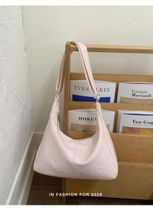 Detail of light pink wrinkled patent leather Hobo bag hanging on a wooden shelf