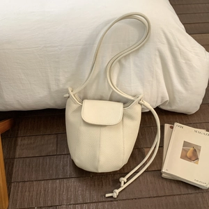 Close-up of cream lychee grain leather bucket bag with flap cover and knot shoulder strap