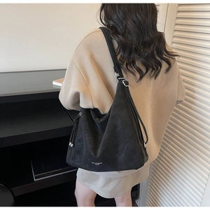 Rear view of a casual large black hobo shoulder bag with an adjustable strap on a model