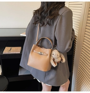 Close-up of light brown lychee grain bucket bag with silver clasp and plush bunny charm