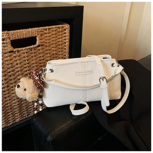 Detail of white leather shoulder bag with cute brown bow bear plush pendant accessory