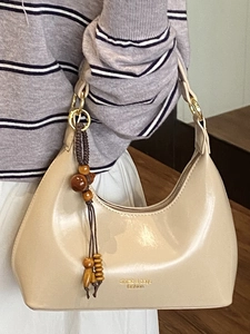 Elegante bolso de hombro beige tipo media luna con colgante de madera y logo dorado