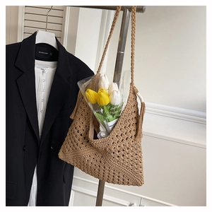 Detail of khaki woven tote bag featuring fringe accents and intricate crochet patterns