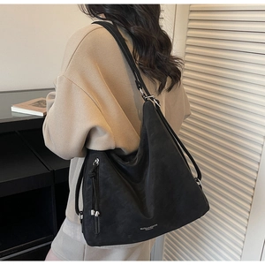 Detail of black large capacity suede tote bag with metal side zipper and brand logo