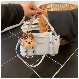Detail of light blue leather handbag with cute teddy bear charm and beaded strap