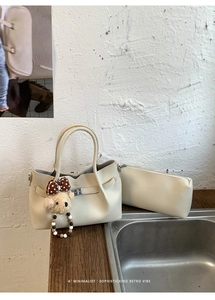 Détail du sac seau blanc crème à texture de lychee avec un petit ours en peluche