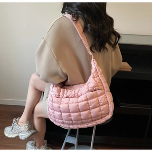 Dettaglio della borsa rosa trapuntata indossata da una modella in un contesto minimalista