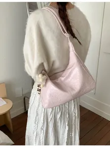 Detail of light pink wrinkled tote bag with fluffy ball charm on an elegant shoulder strap
