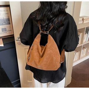 Detailed view of a light brown suede tote bag featuring a metallic side zipper and soft texture
