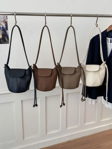 Detail view of bucket bags in four colors hanging on a rod with drawstring texture