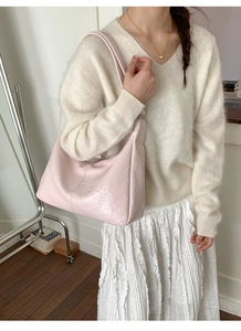 Close-up of light pink hobo bag featuring soft pleated glossy texture and wide strap
