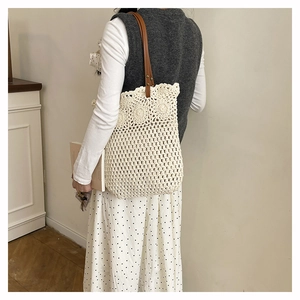 Détail d'un sac cabas en crochet évidé avec motifs floraux et anses en cuir marron