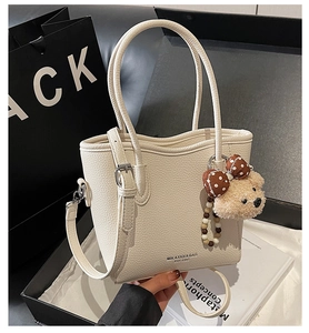 Détail du sac seau en cuir grainé blanc cassé avec une adorable peluche d'ours