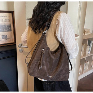 Detail of dark brown faux suede hobo bag with zip accents and branded logo lettering