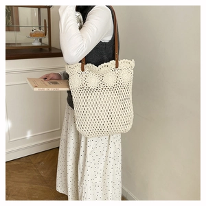 Détail du motif tissé ajouré et des poignées en cuir marron sur le sac cabas blanc cassé