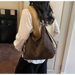 Detail shot of the large dark brown suede tote bag with subtle logo branding on the bottom