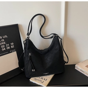 Detailed macro view of the silver brand logo and sleek black matte fabric of this tote bag
