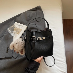 Detail of black pebbled leather bucket bag with silver hardware and plush bunny charm
